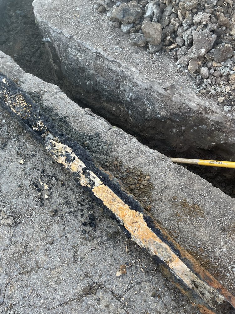 Excavated sewer line showing corroded pipe and cable during repair